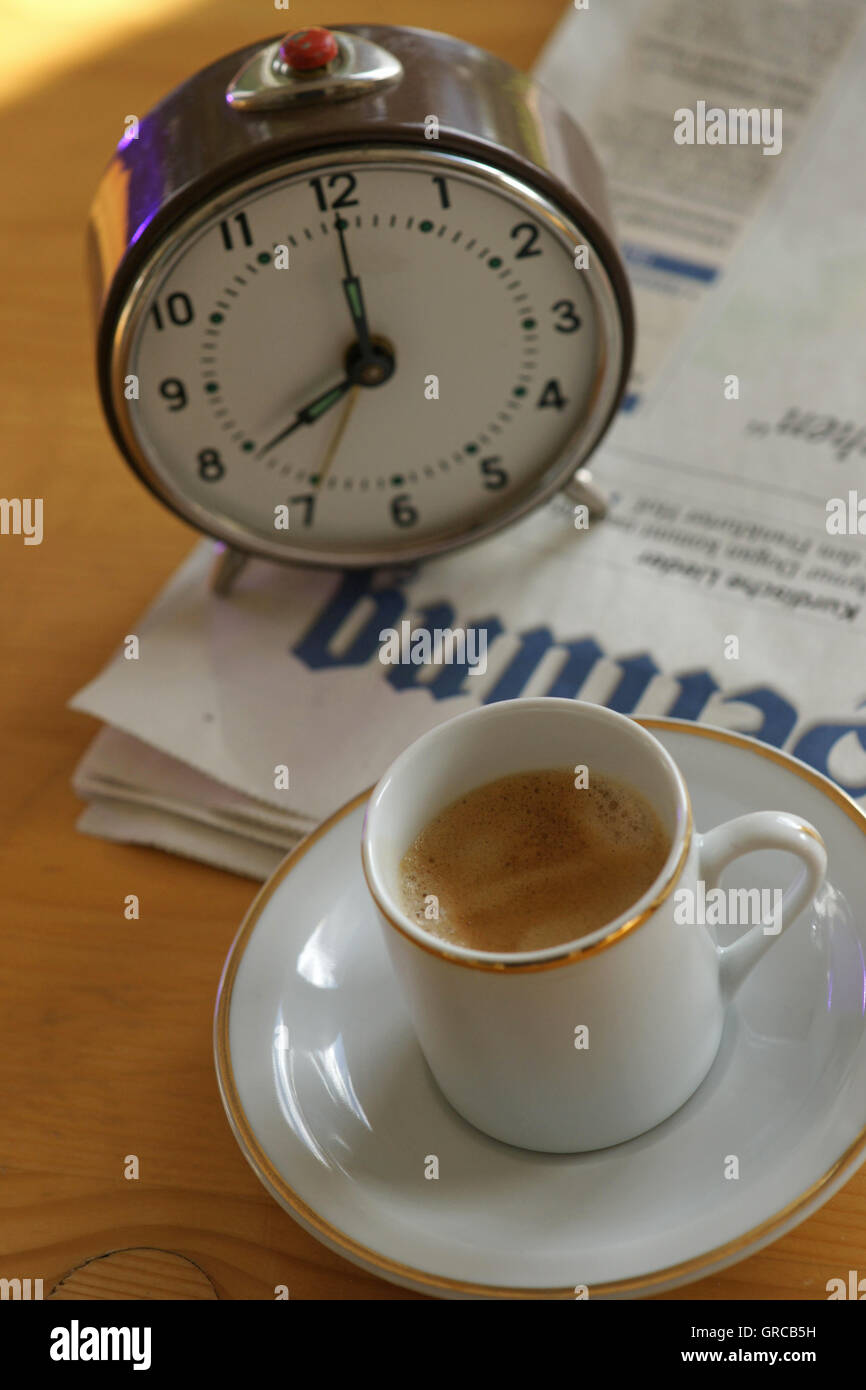 Der Tag beginnt mit dem Wecker, eine Tasse Kaffee und die Zeitung Stockfoto