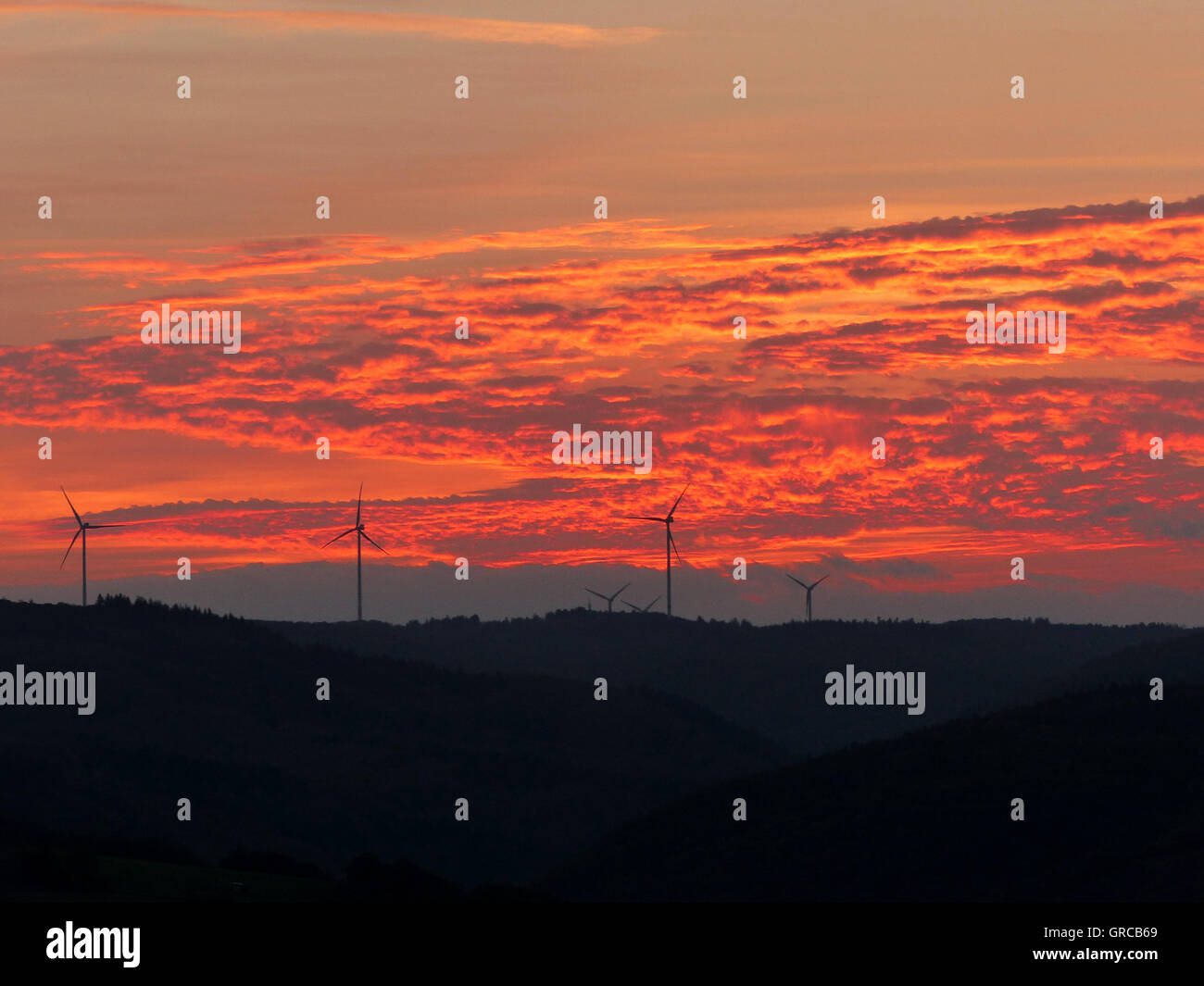 Hunsrück-Hügel mit Windkraftanlagen am Horizont In den roten Sonnenuntergang Stockfoto