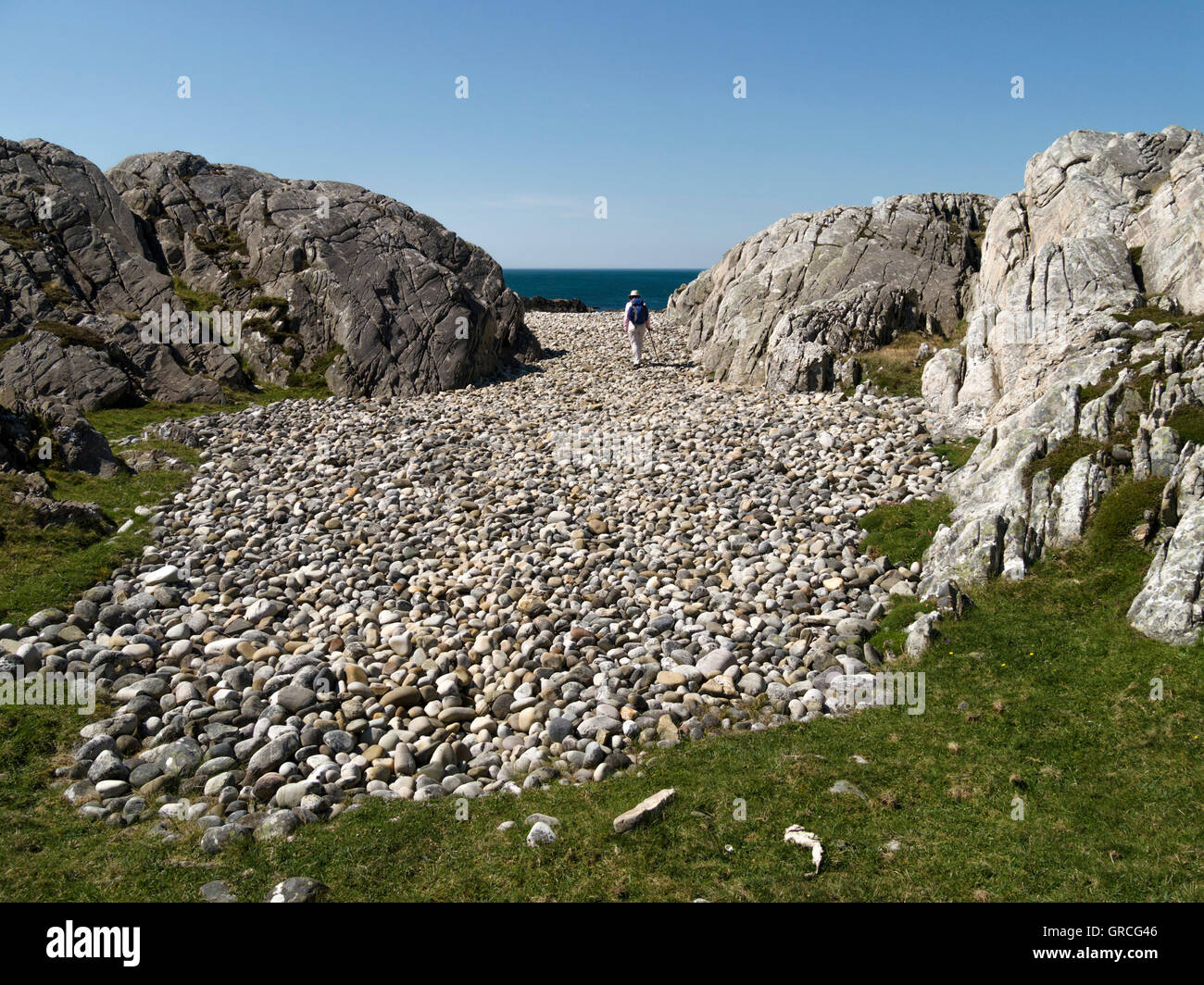 Einsame weibliche Walker auf erhöhten Kiesstrand, Ardskenish, Insel Colonsay, Schottland, Vereinigtes Königreich. Stockfoto