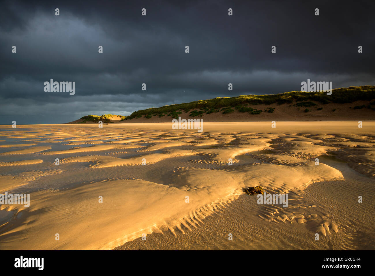 Dramatische stimmungsvolle Licht am Strand in der Abenddämmerung in Bamburgh, Northumberland England UK Stockfoto