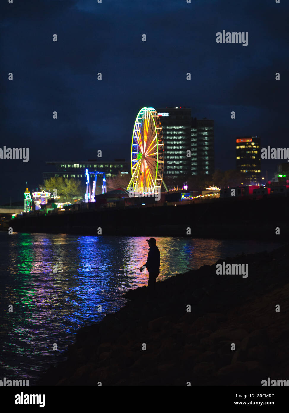 Ein Fischer in der Nacht In Köln vor dem Hintergrund der Kirmes Stockfoto