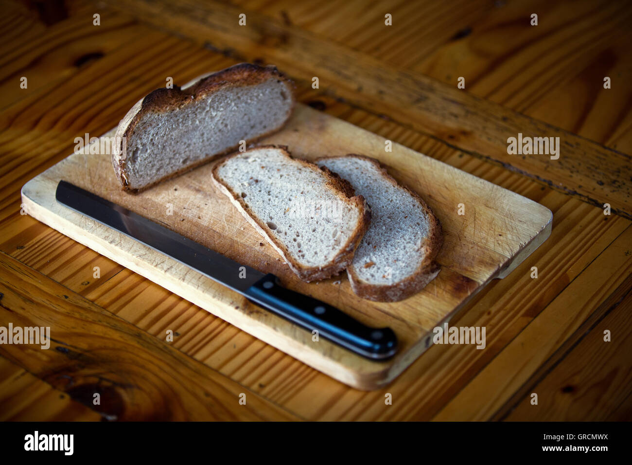 Frühstücksbrettchen mit Brotlaib auf Holztisch Stockfoto