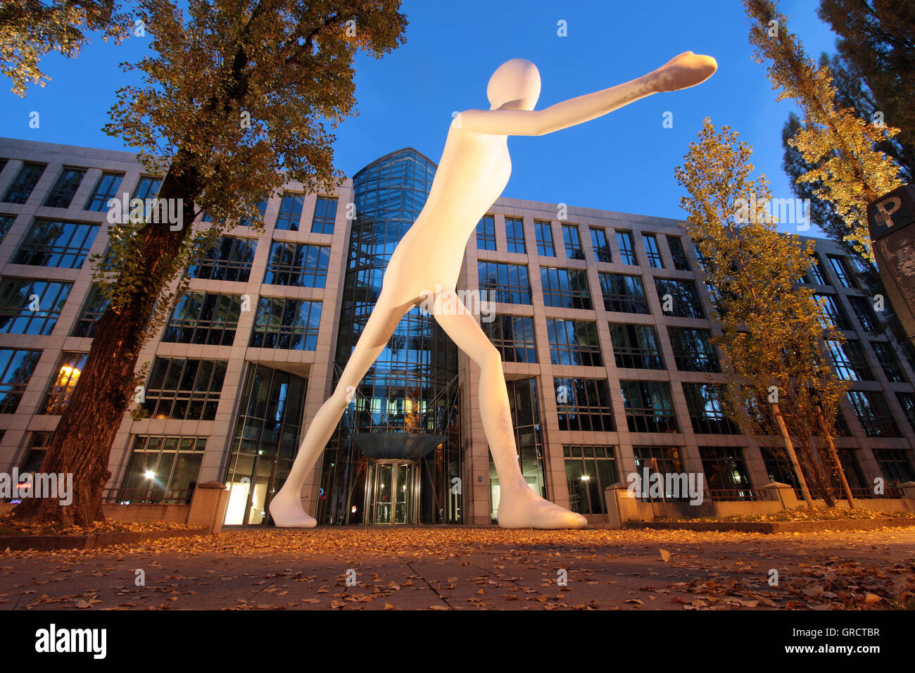 Sculpure Wandern Mann vor Versicherungsgesellschaft Münchener Rück in der Abenddämmerung Stockfoto