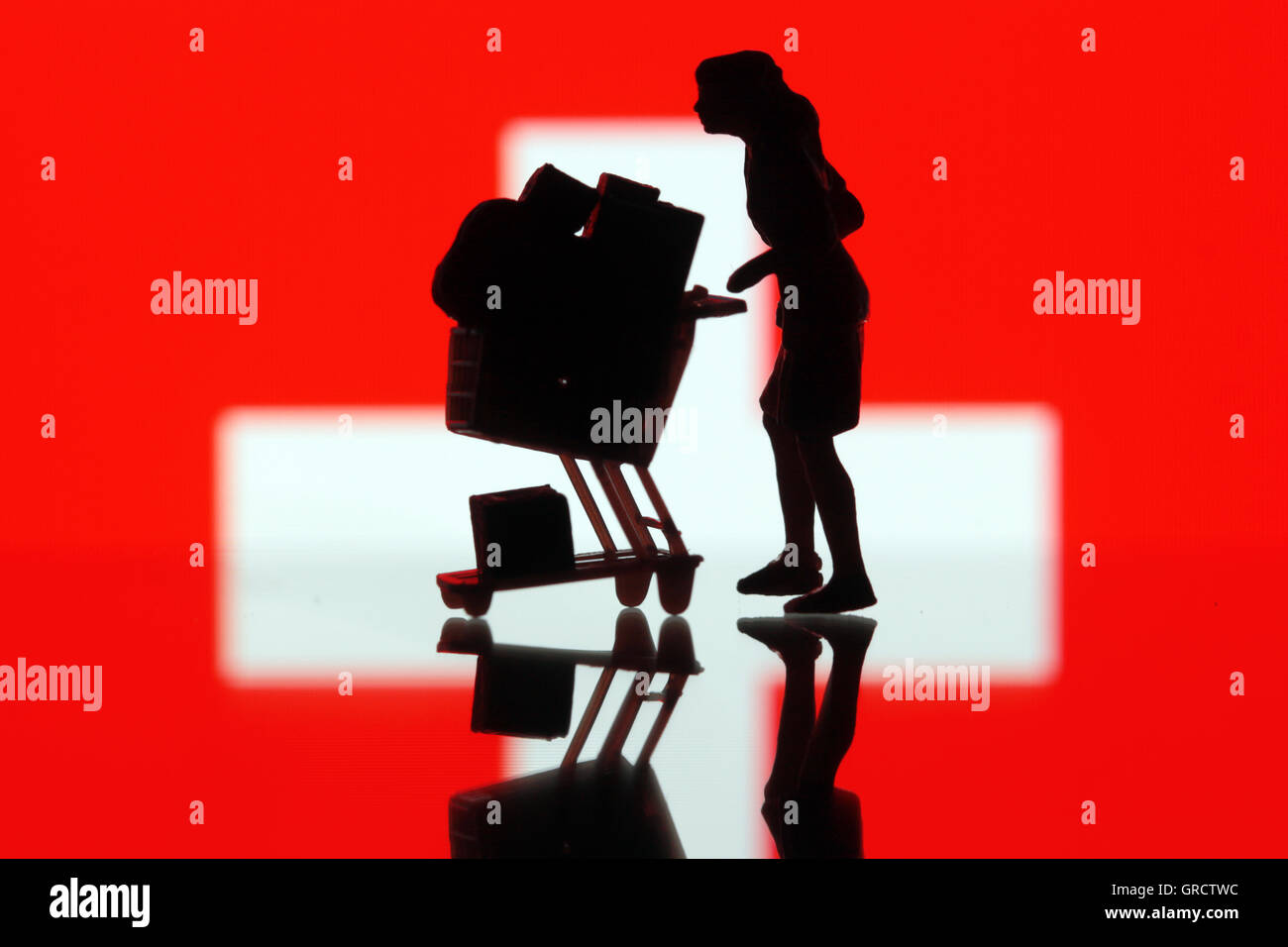 Schweizer Flagge mit Frau und voller Einkaufswagen Stockfoto