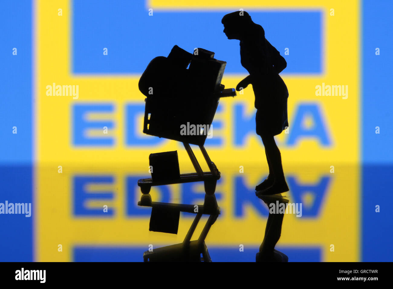 Frau mit vollen Einkaufswagen und Logo von Edeka Stockfoto