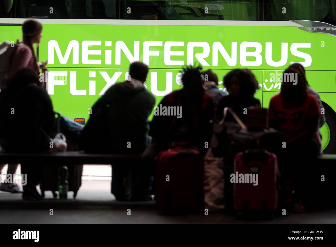Long Distance Bus Meinfernbus mit Silhouetten des Wartens Reisende In München Stockfoto