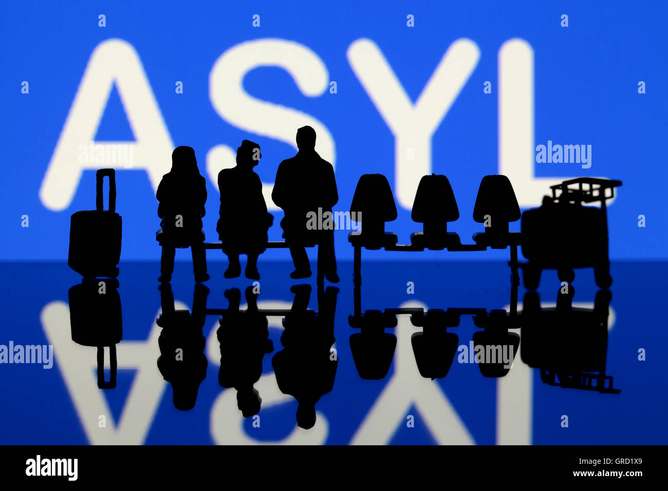 Miniaturfiguren mit Wort Asyl zu sitzen Stockfoto