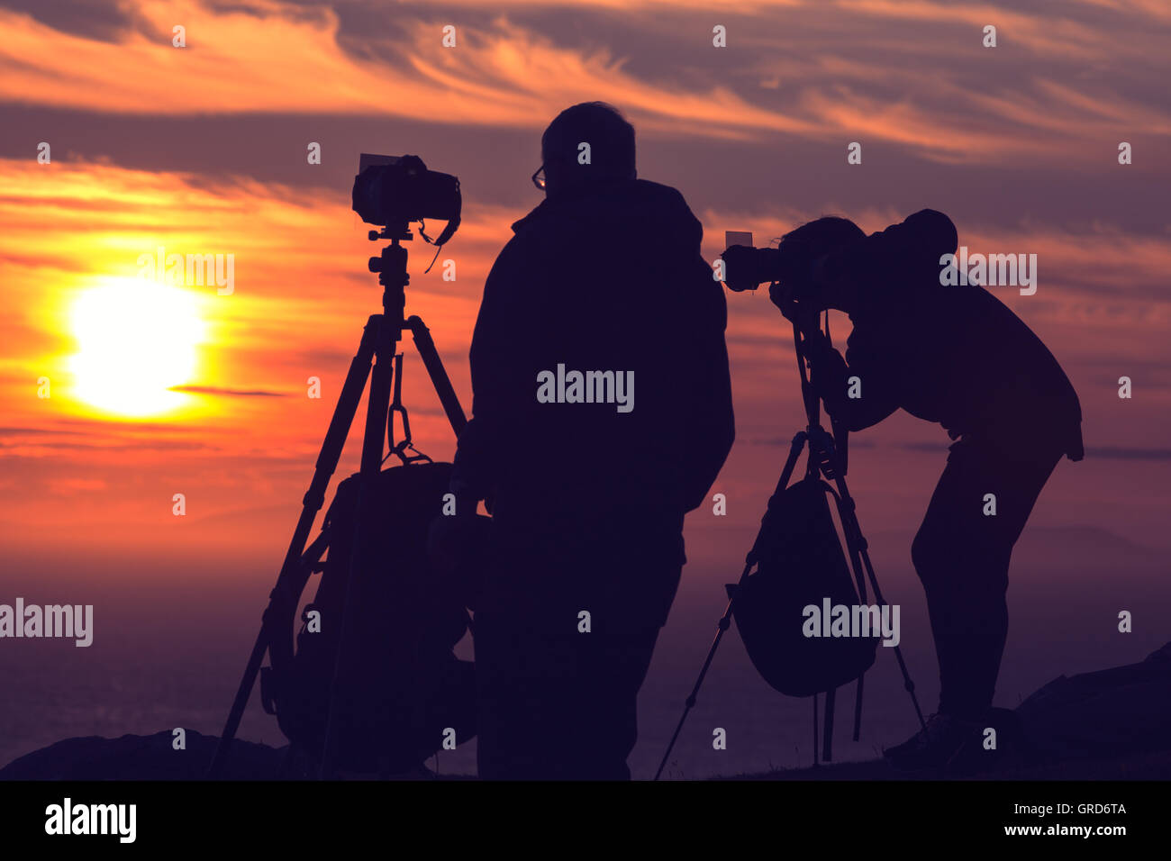 Fotografen-Silhouetten auf Klippe gegen bunte Dämmerung Himmel Stockfoto