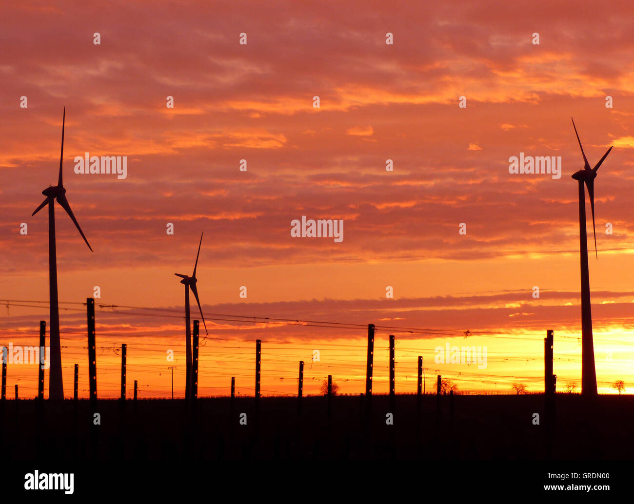 Windenergieanlagen gegen feurige rote Sunrise Stockfoto