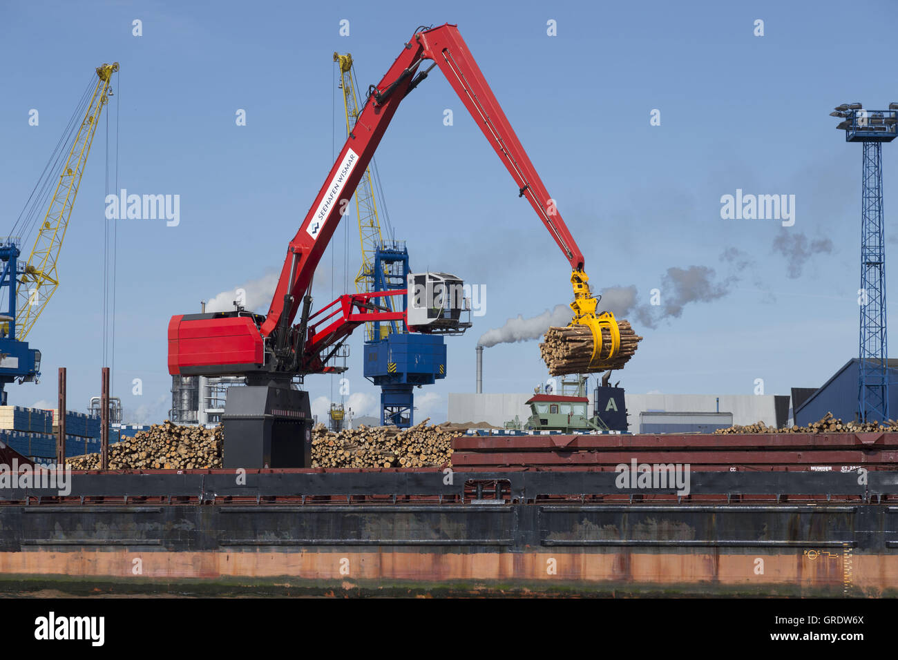 Große rote Bagger entladen Holz von einem Cargo-Frachter im Hafen von Wismar Stockfoto