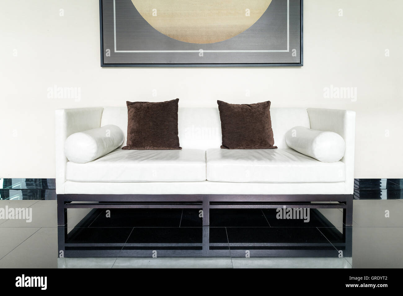 Weißes Ledersofa und braune Kissen in Lounge im Wohnzimmer im Haus. Stockfoto
