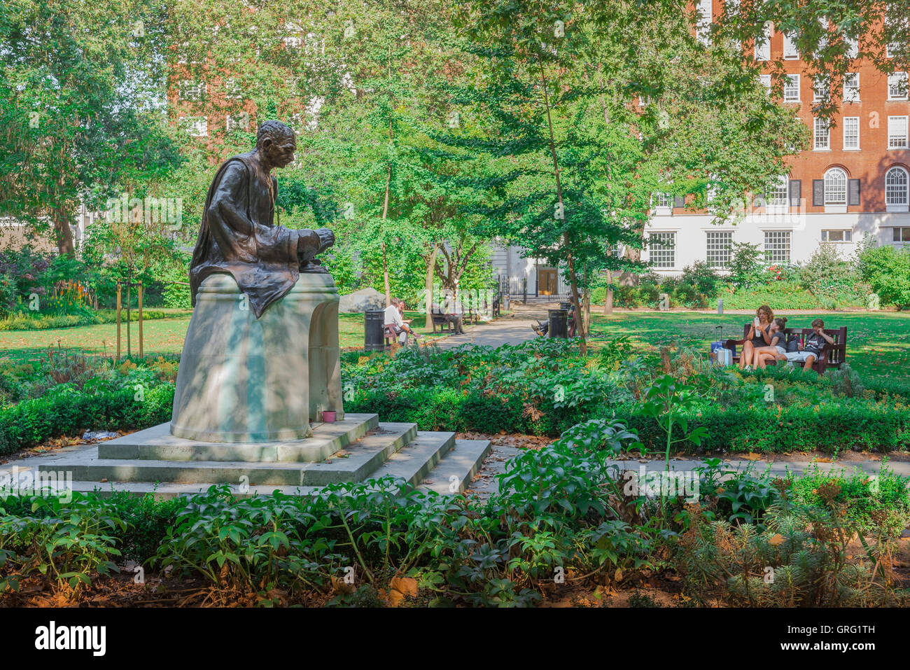 Tavistock Square in London, entspannen, Leute in der Nähe eine Statue von Mahatma Gandhi in Tavistock Square, Bloomsbury, UK. Stockfoto