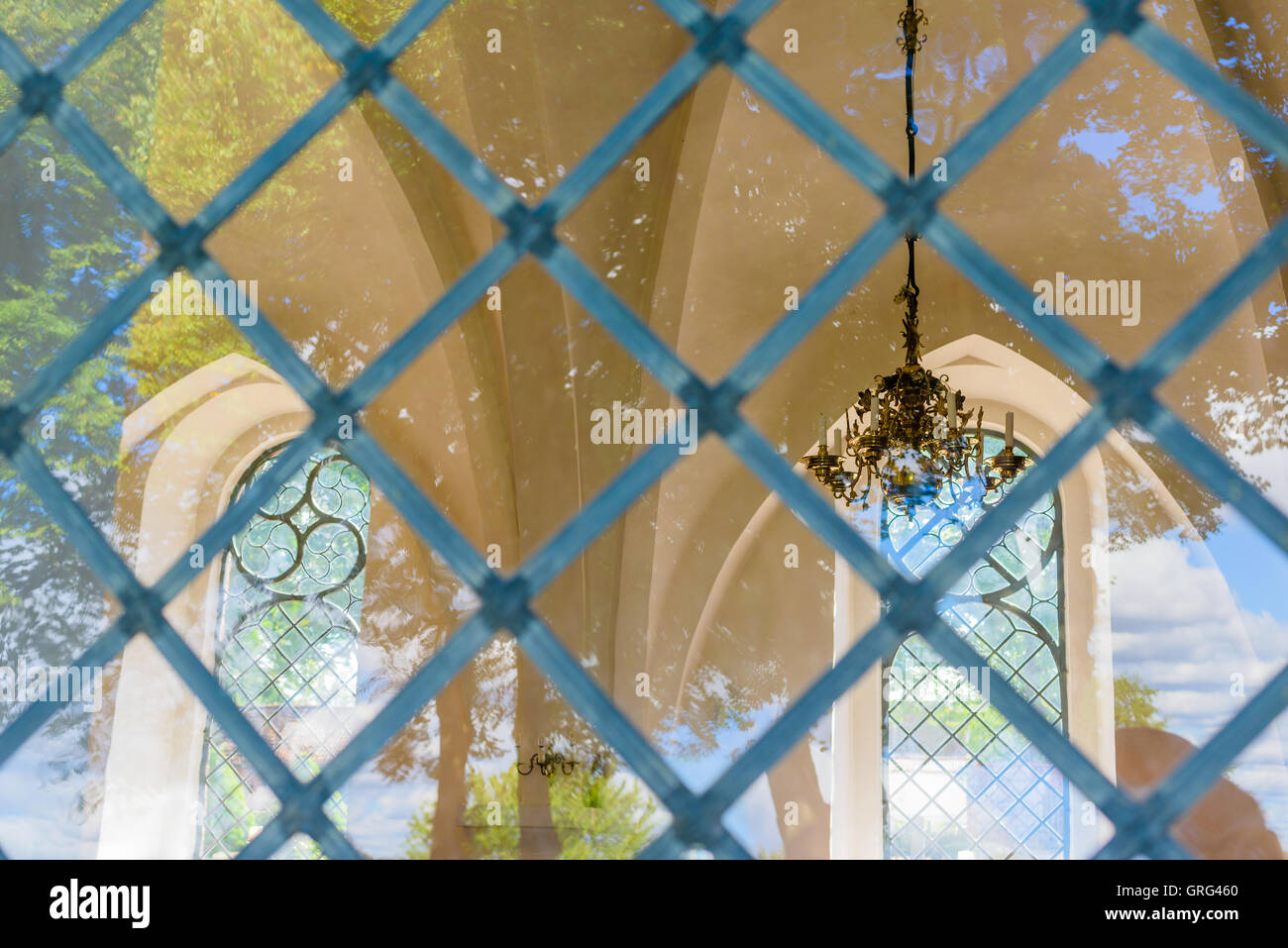 Hurva, Schweden - 5. September 2016: Ein Blick durch eines der Kirchenfenster schmähen eine schöne Deckenleuchte und ein weiteres Fenster auf der Stockfoto