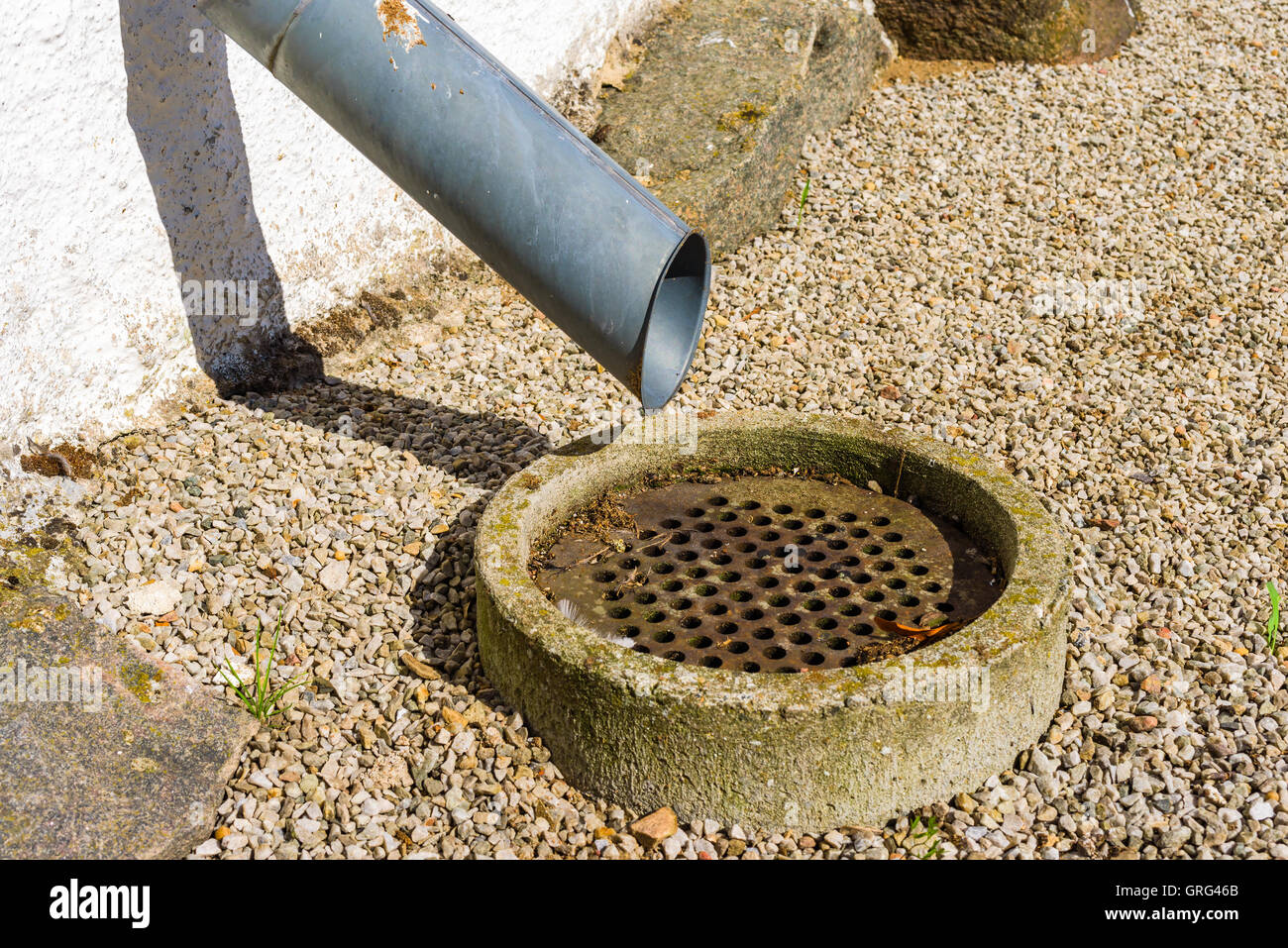 Outdoor-Fallrohr endet oberhalb einer geriebenen Abwasserrohr. Stockfoto
