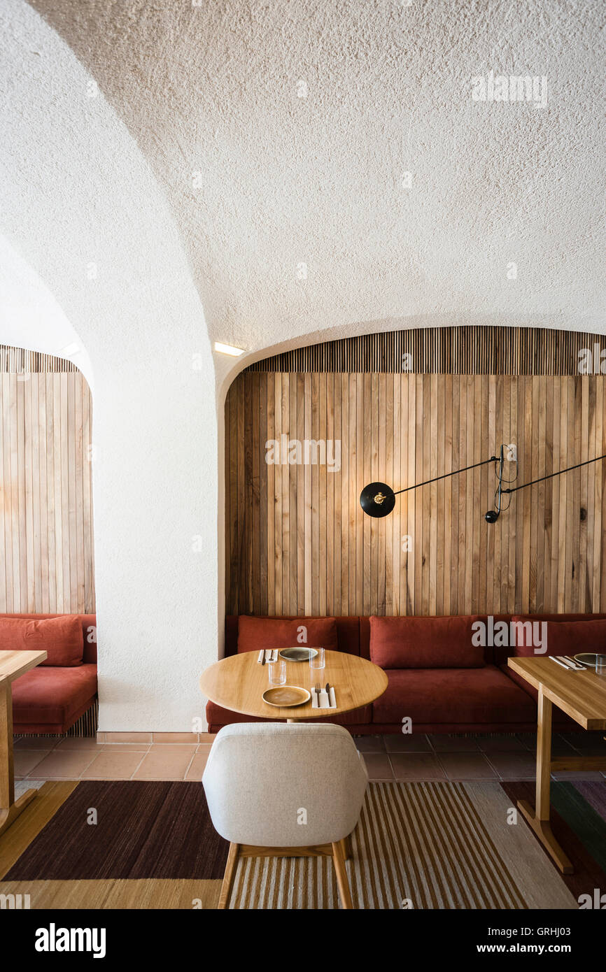 Detailansicht der hölzernen Wand und Cantilever-Lampe, Teppiche von Nani Marquina. Green Spot Restaurant, Barcelona, Spanien. Architekt: Isay Weinfeld, 2016. Stockfoto