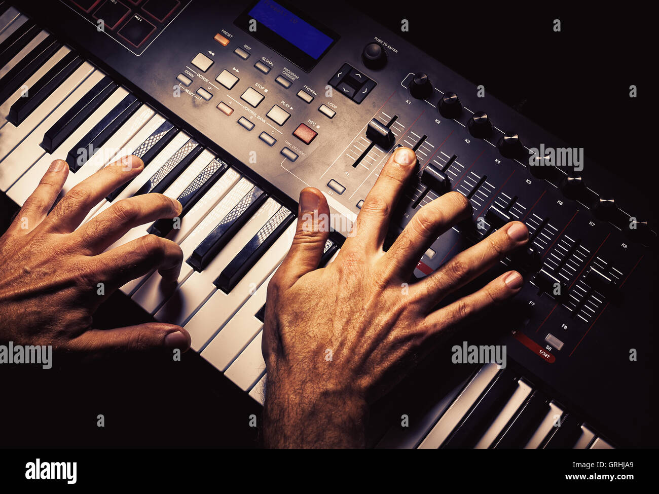 Einzelheiten über eine moderne MIDI-Keyboard mit männlichen Händen drauf spielen. Stockfoto