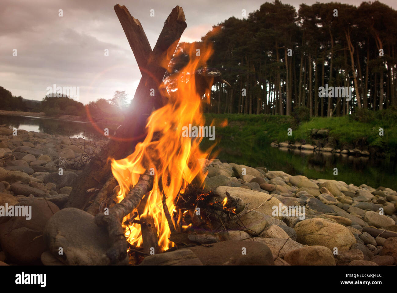 Feuer an einem Fluss Kiesstrand Campen Stockfoto