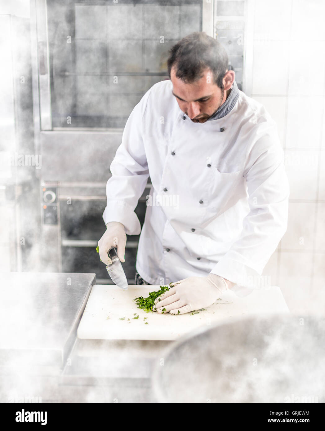 Koch schneiden Petersilie auf weiße Schneidebrett Stockfoto