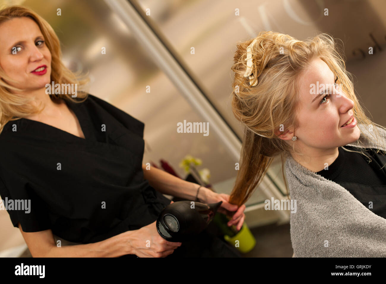 professionelle Friseur am Arbeitsplatz - Friseur, Frisur, um schöne junge blonde Kunde in einem professionellen studio Stockfoto