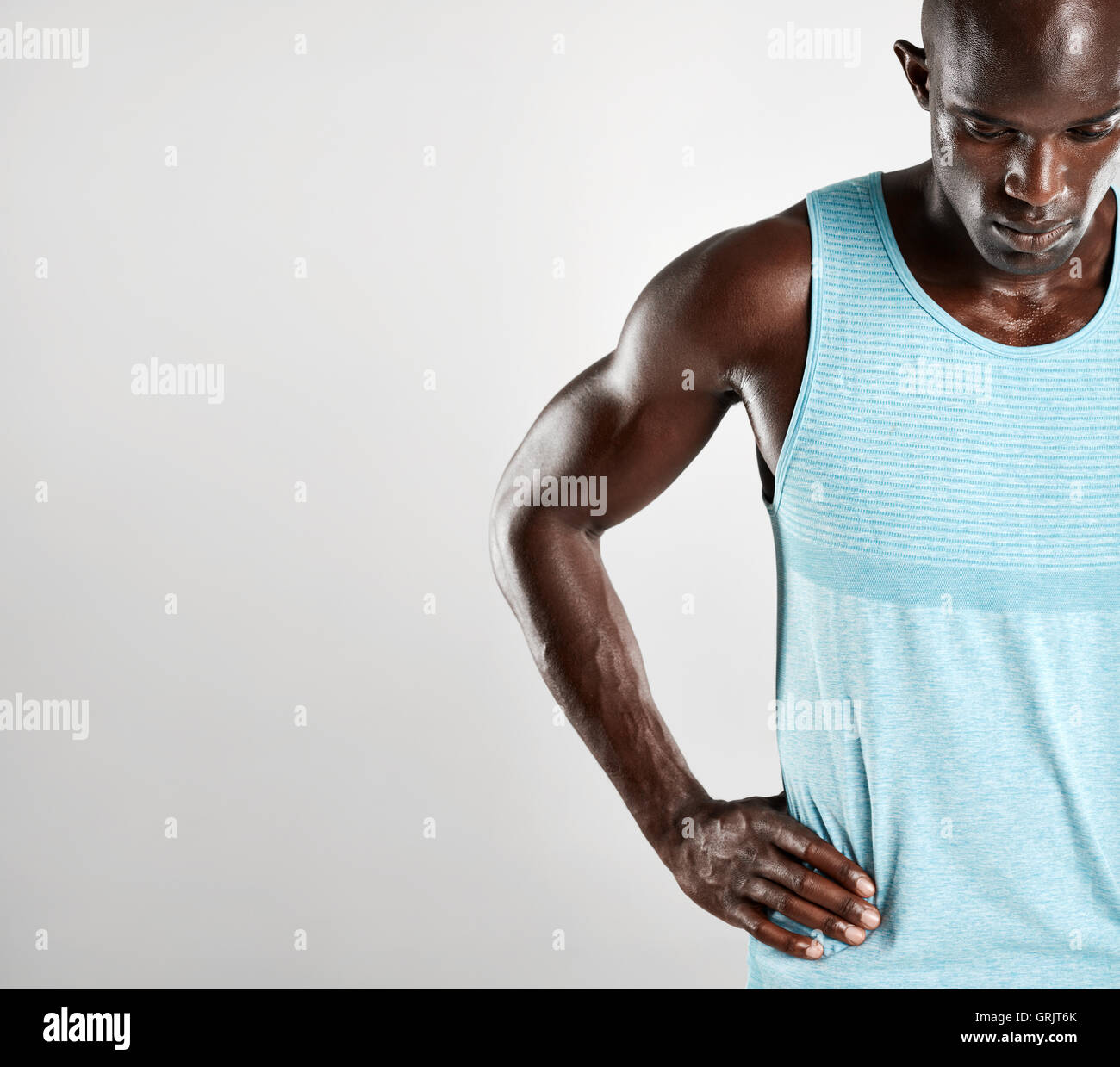 Schuss von muskulösen jungen afrikanischen Mann vor grauem Hintergrund mit textfreiraum beschnitten. Männliches Model stehend mit den Händen Stockfoto