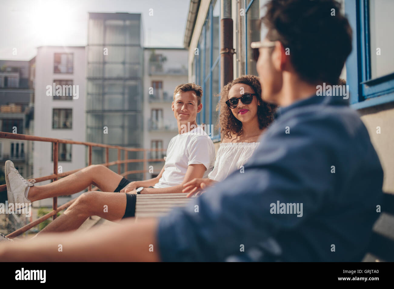 Schuss von junge Frau sitzt mit ihren Freunden im Café im Freien. Gruppe von Jugendlichen, die in einen Balkon entspannen. Stockfoto