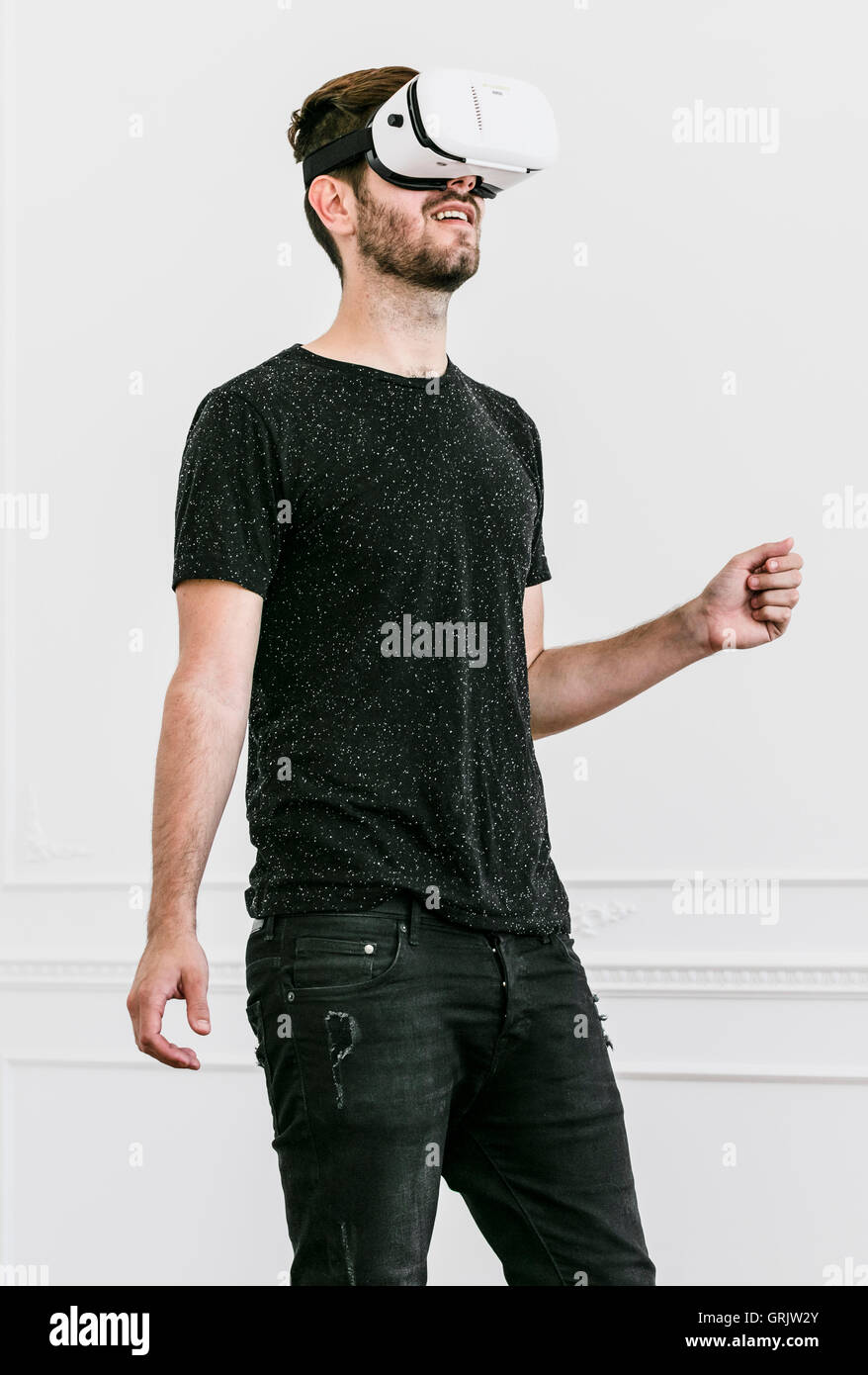Ein junger Mann steht mit einer virtual-Reality-Kopfhörer in einem Raum Stockfoto