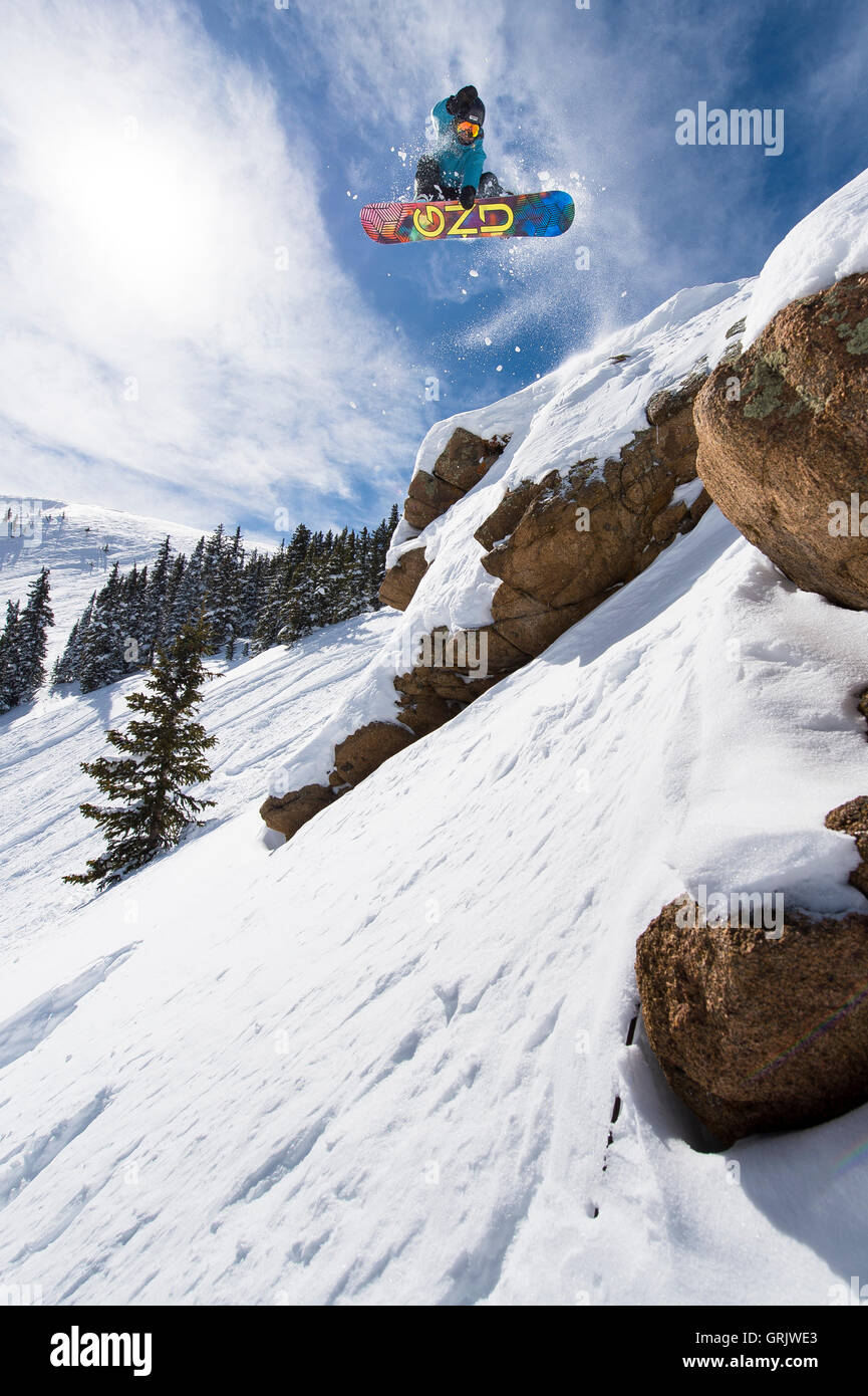 Profi-Snowboarder Sandra Hillen abspringen eine Felswand in Colorado an einem sonnigen Tag Stockfoto