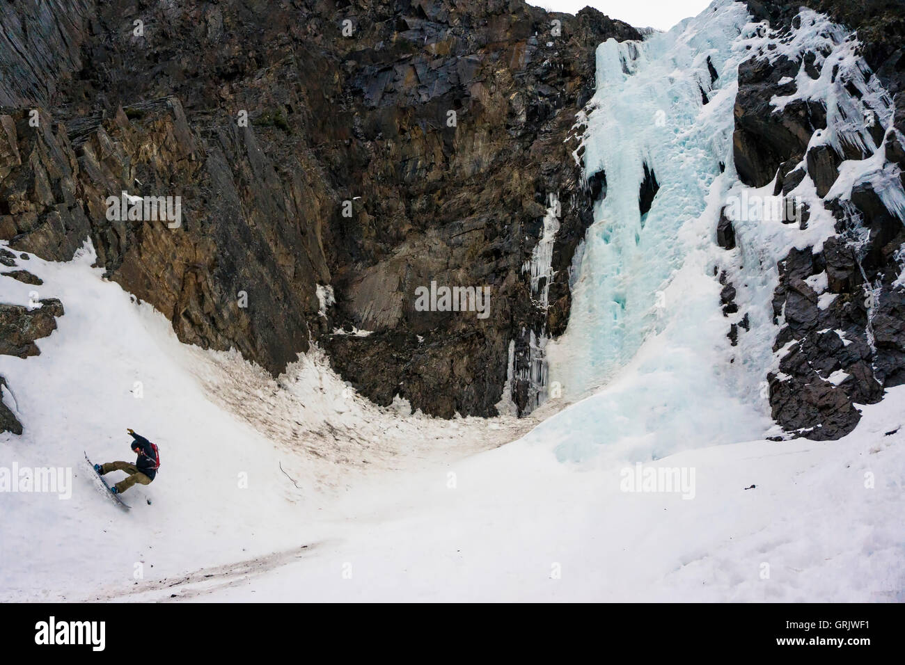 Snowboarden macht einen Schrägstrich unten einen Eiswasserfall Stockfoto