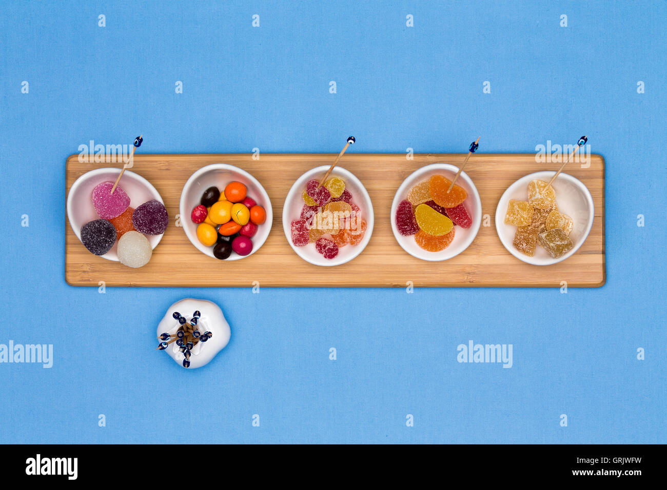 Schalen mit verschiedenen gummiartige Bonbons mit herauskristallisiert Zuckerguss, Brustbeeren, Gummibärchen und fruchtige Zahnfleisch in einer Reihe auf einem Woo angeordnet Stockfoto