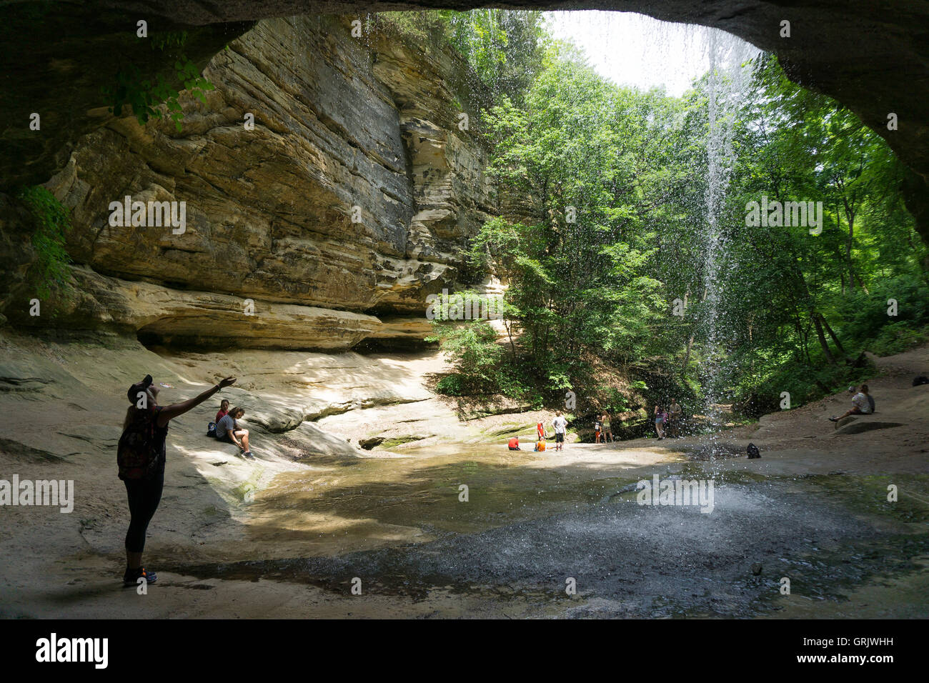 Eine Frau berührt das Wasser aus einem fallenden Wasserfall im gehungert Rock State Park Stockfoto