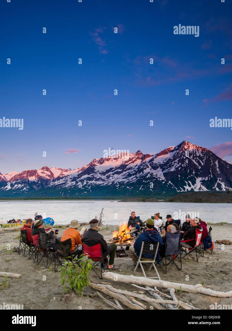 Sparren sitzen um ein Lagerfeuer bei Sonnenuntergang, Alsek River Stockfoto