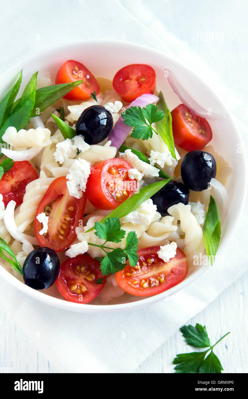 Nudelsalat mit Gemüse, Oliven und Feta auf weißem Hintergrund Stockfoto