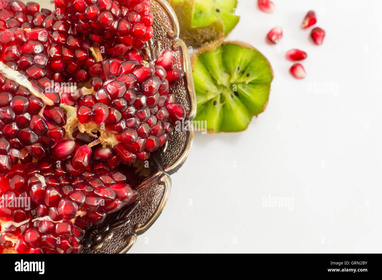 Saftige ganze Granatapfel und Kiwi auf weißem Hintergrund Stockfoto