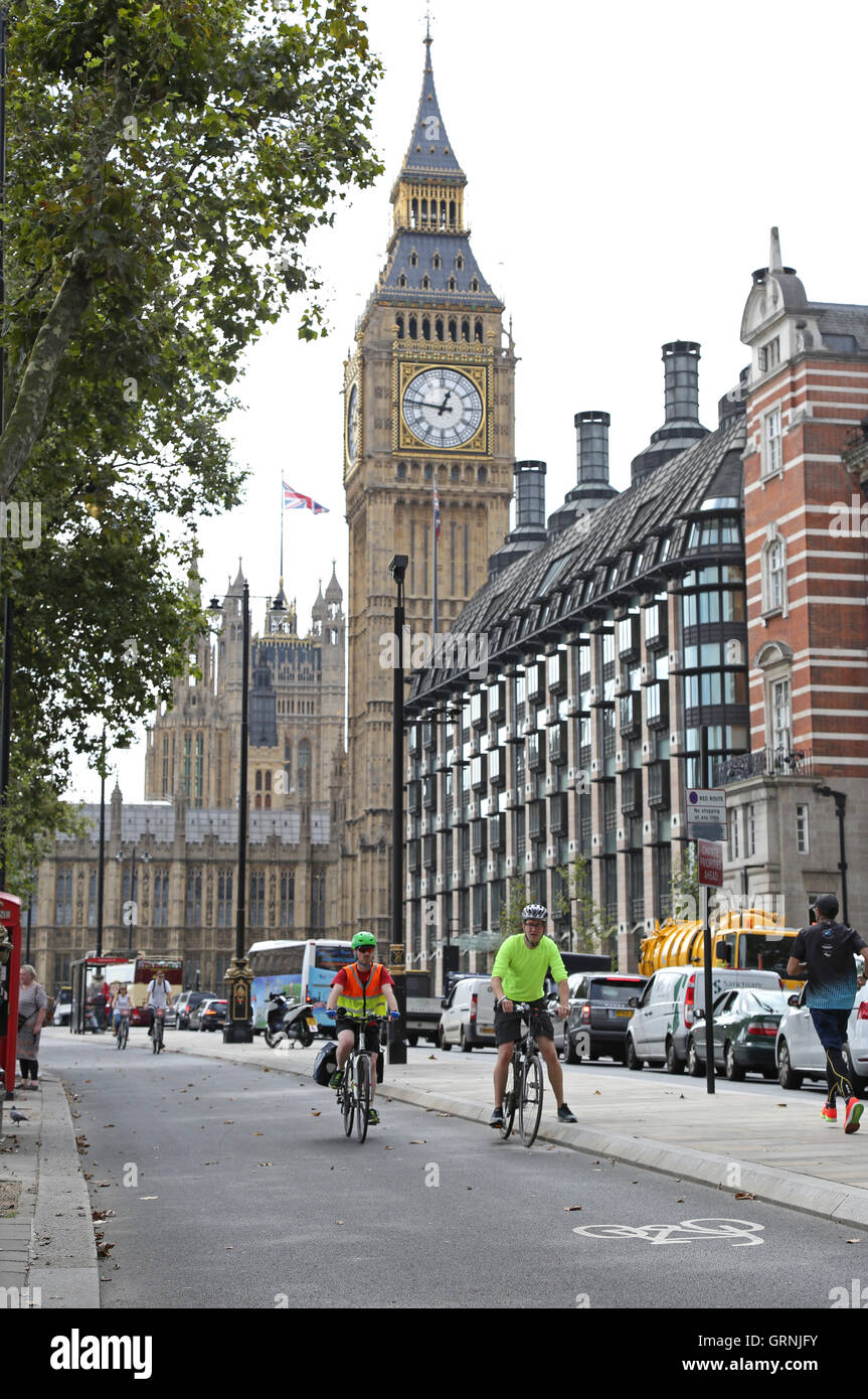 Radfahrer nutzen Londons neuen, getrennten Radweg am Victoria Embankment. Big Ben zeigt im Hintergrund. Stockfoto