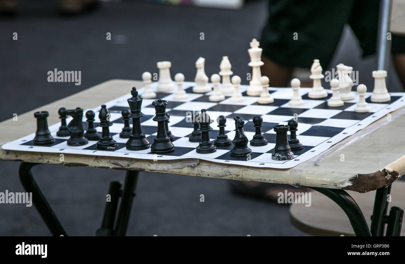 Ein Schachbrett auf einen abgenutzten Klapptisch mit den Stücken, die für die Aufnahme des Spiels festgelegt. Stockfoto