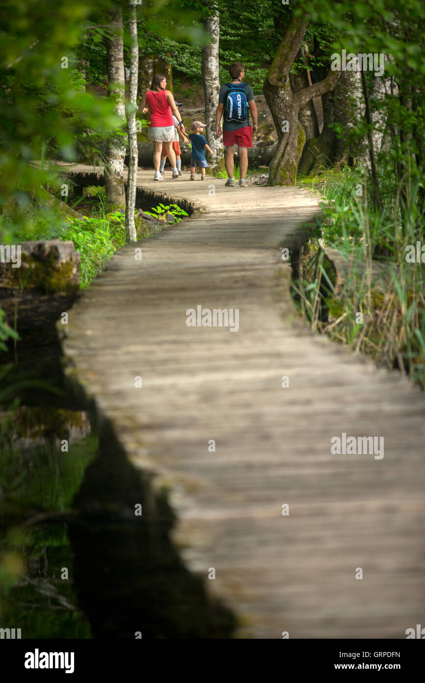 Eine touristische Familie Bummeln auf einem hölzernen Steg (Nationalpark Plitvicer Seen - Kroatien). Urlauber auf einem Holzsteg. Stockfoto
