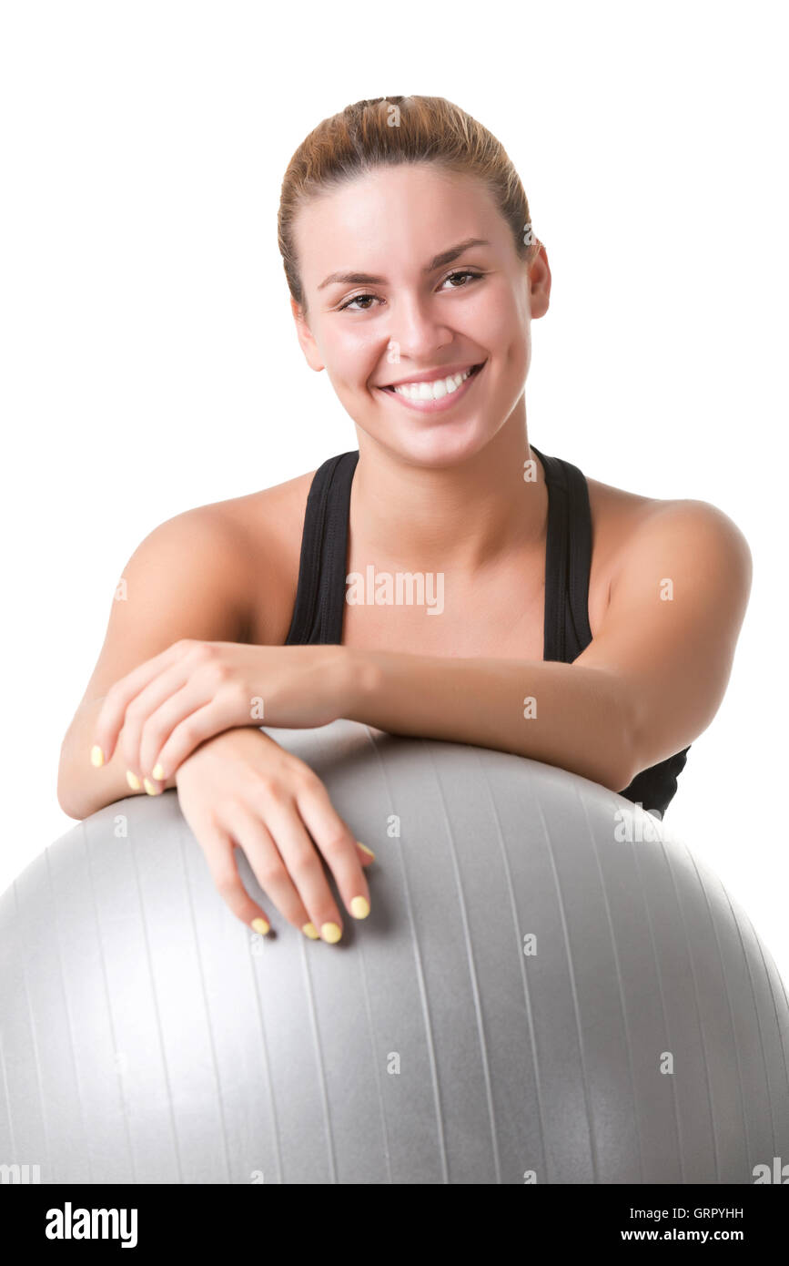 Fit Frau sitzen und halten einen Pilates-Ball auf dem Boden isoliert in weiß Stockfoto