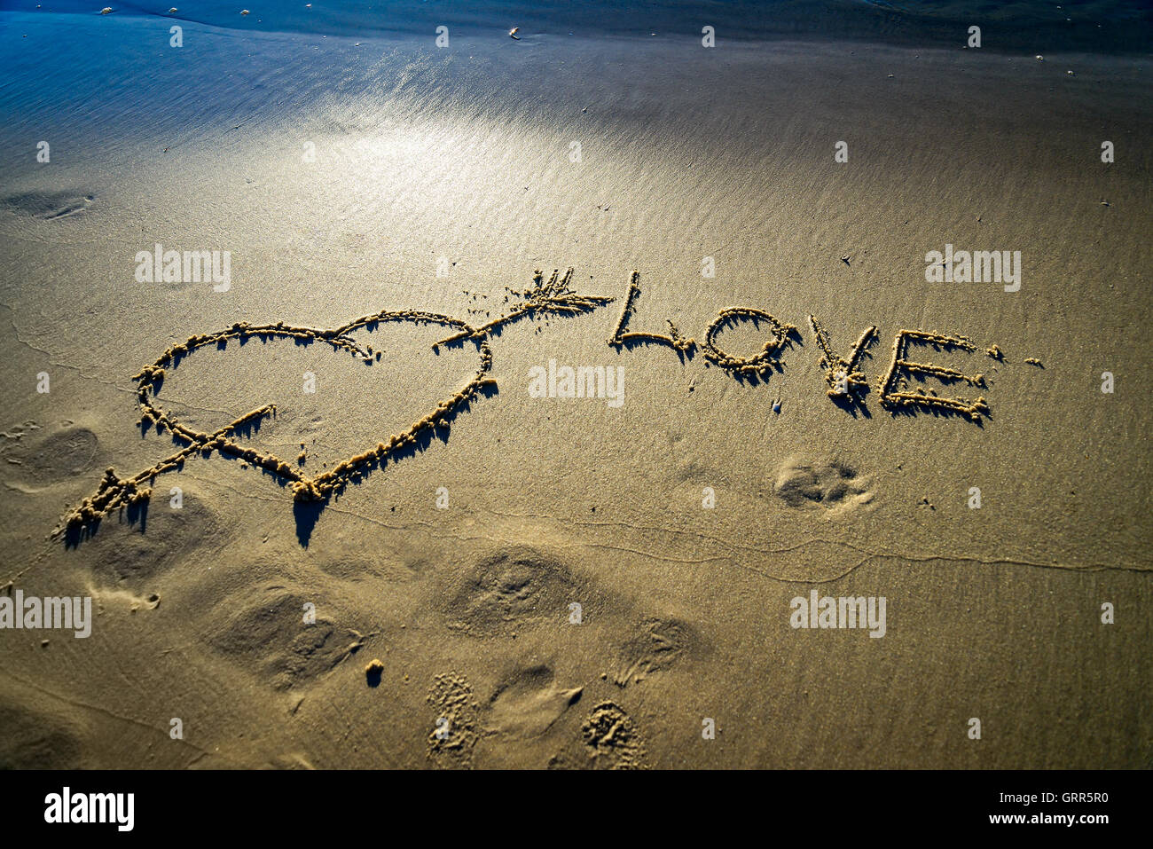 Herz und Pfeil gezeichnet auf dem Sand am Strand.  Liebe-Konzept Stockfoto