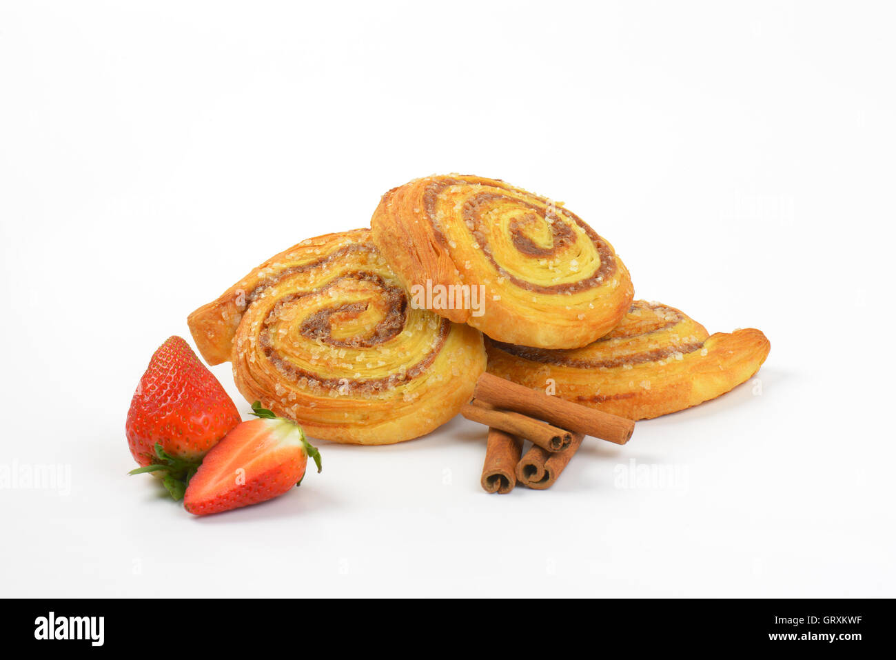 süße Zimtbrötchen, Zimtstangen und Erdbeeren auf weißem Hintergrund Stockfoto