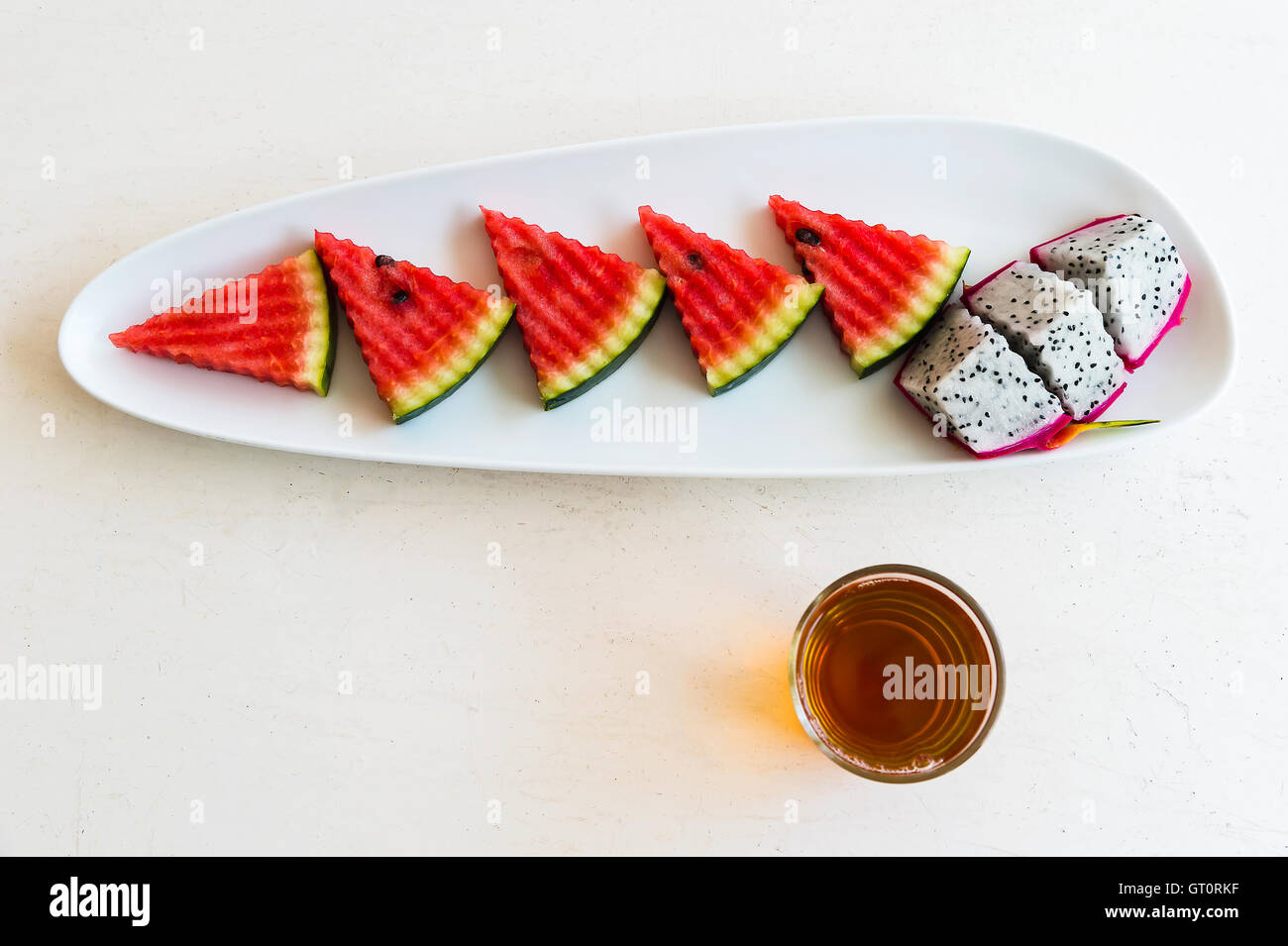 in Scheiben geschnittenen Wassermelone und Drachenfrucht auf Teller mit heißem Tee im Glas Stockfoto