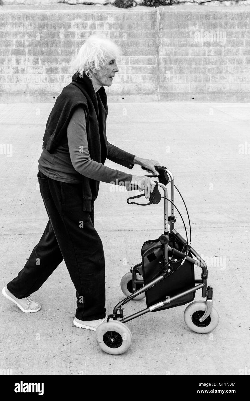 Eine ältere Frau zu Fuß mit einem Rollator zu Fuß Hilfe, Rottingdean, Sussex, UK Stockfoto