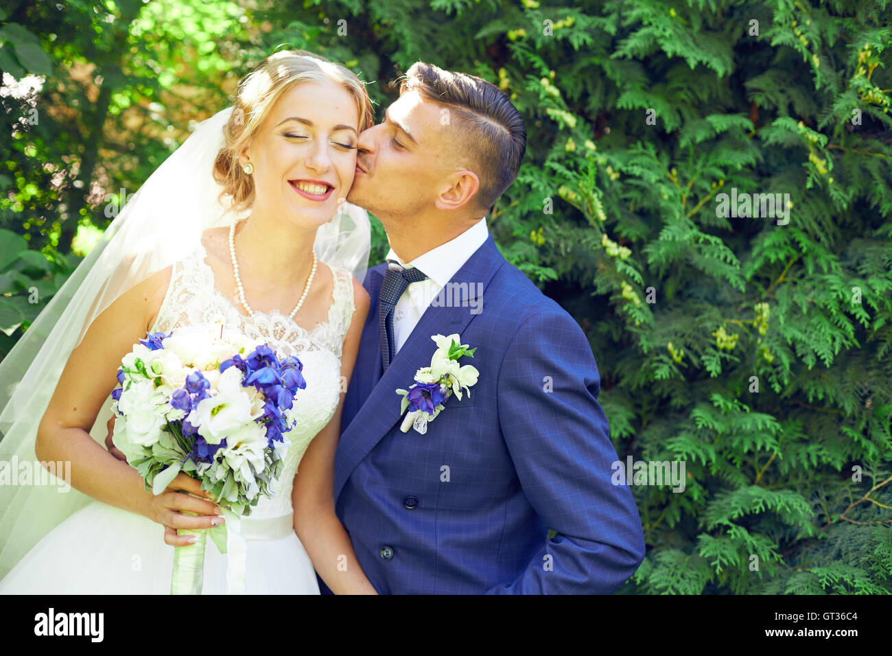Schöne Braut und Bräutigam küssen am Tag ihrer Hochzeit im freien Stockfoto