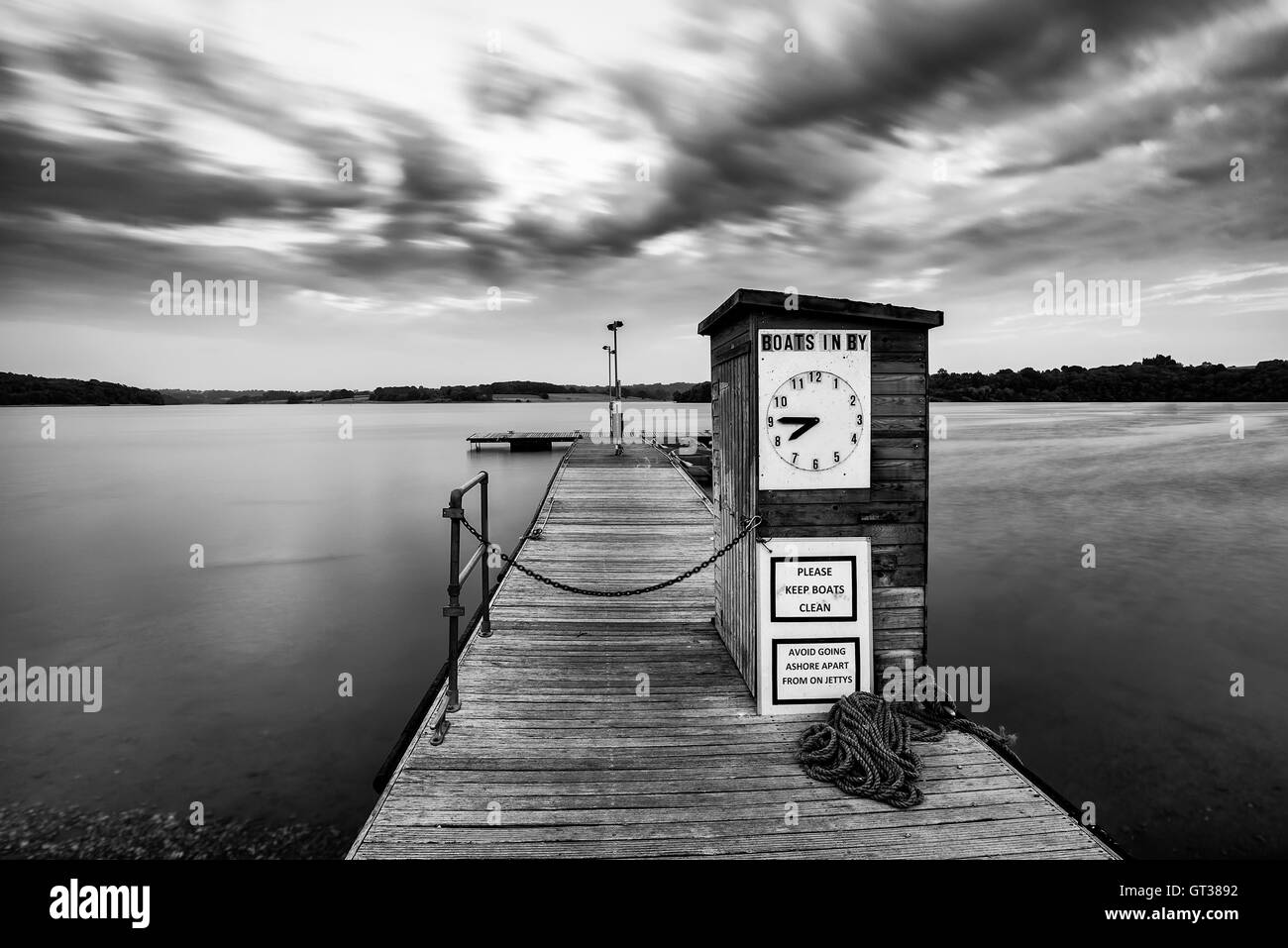 Landschaftsbild der schönen bei Sonnenuntergang von Freizeitbooten vertäut am Steg im See am Ende der Sommertag in schwarz / weiß Stockfoto