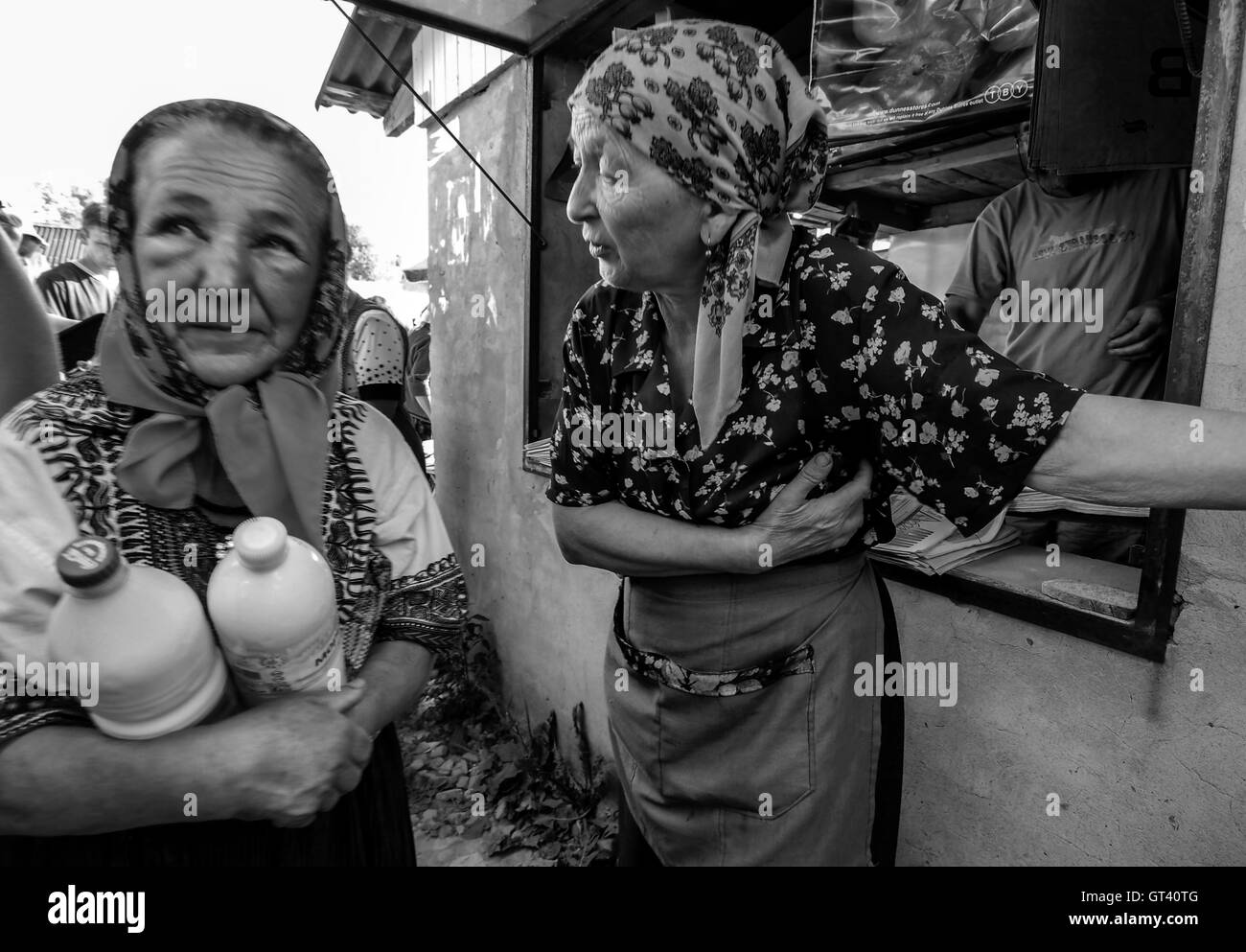 Zwei alte Frauen, die Milch auf dem Markt verkaufen sprechen am Markt in der Stadt von Kosov, Ivano-Frankivsk Oblast, Ukraine Stockfoto