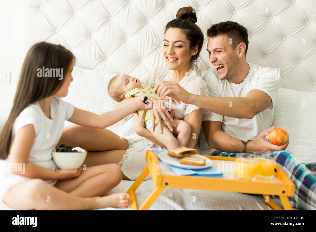 Mutter, Vater, Kind und kleine Mädchen auf dem Bett im Zimmer Stockfoto