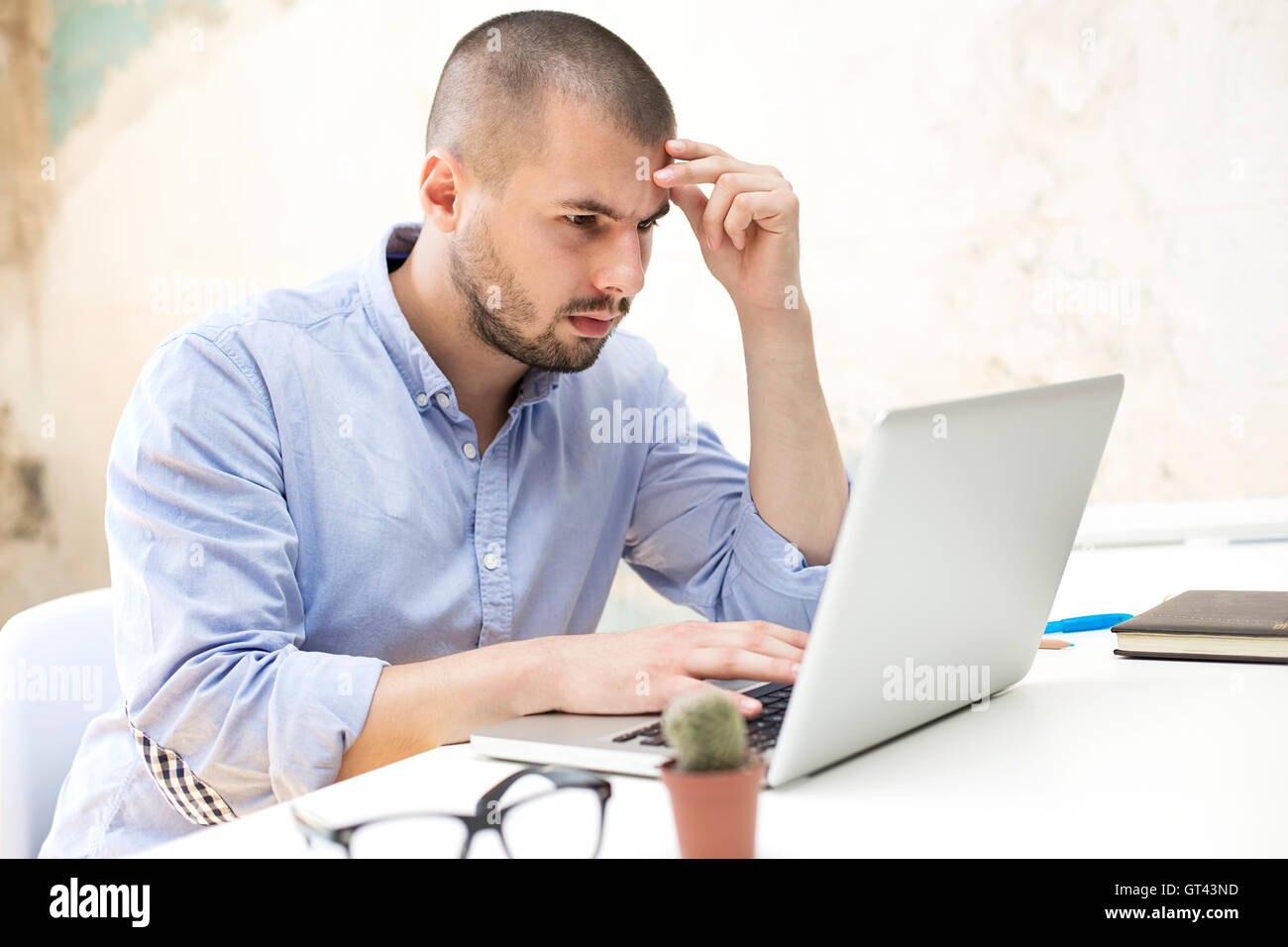 Junger Mann arbeiten am Laptop in He-Büro Stockfoto