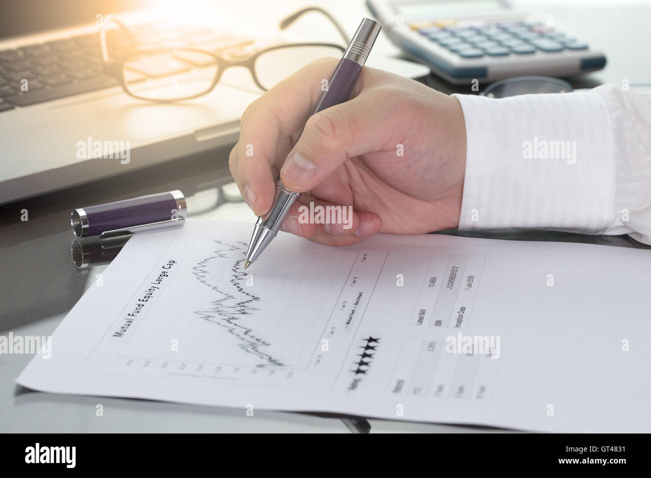 Geschäftsmann oder Fonds-Manager überprüfen Investmentfonds Informationen mit Leistung Liniendiagramm und Benchmark mit Stift-Rechner und com Stockfoto