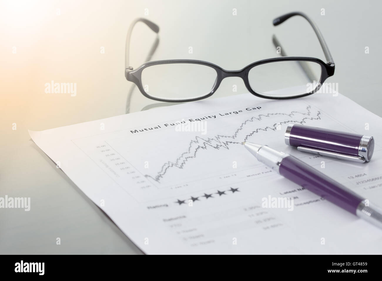 Investmentfonds-Informationen mit Leistung Liniendiagramm und Benchmark mit Stift und Gläser. Stockfoto