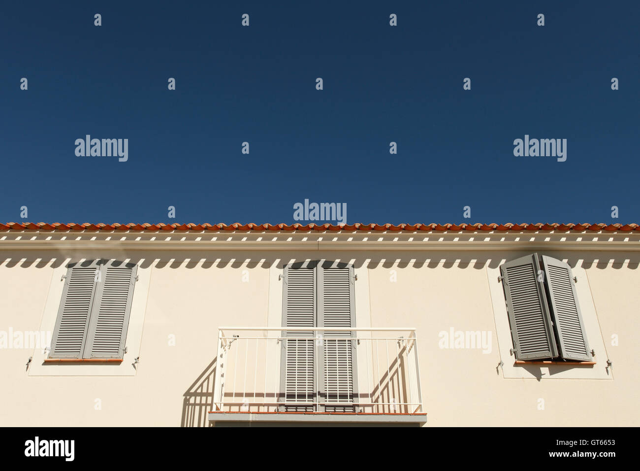 Geschlossene Fensterläden auf einem weiß getünchten Haus in der Sonne Stockfoto