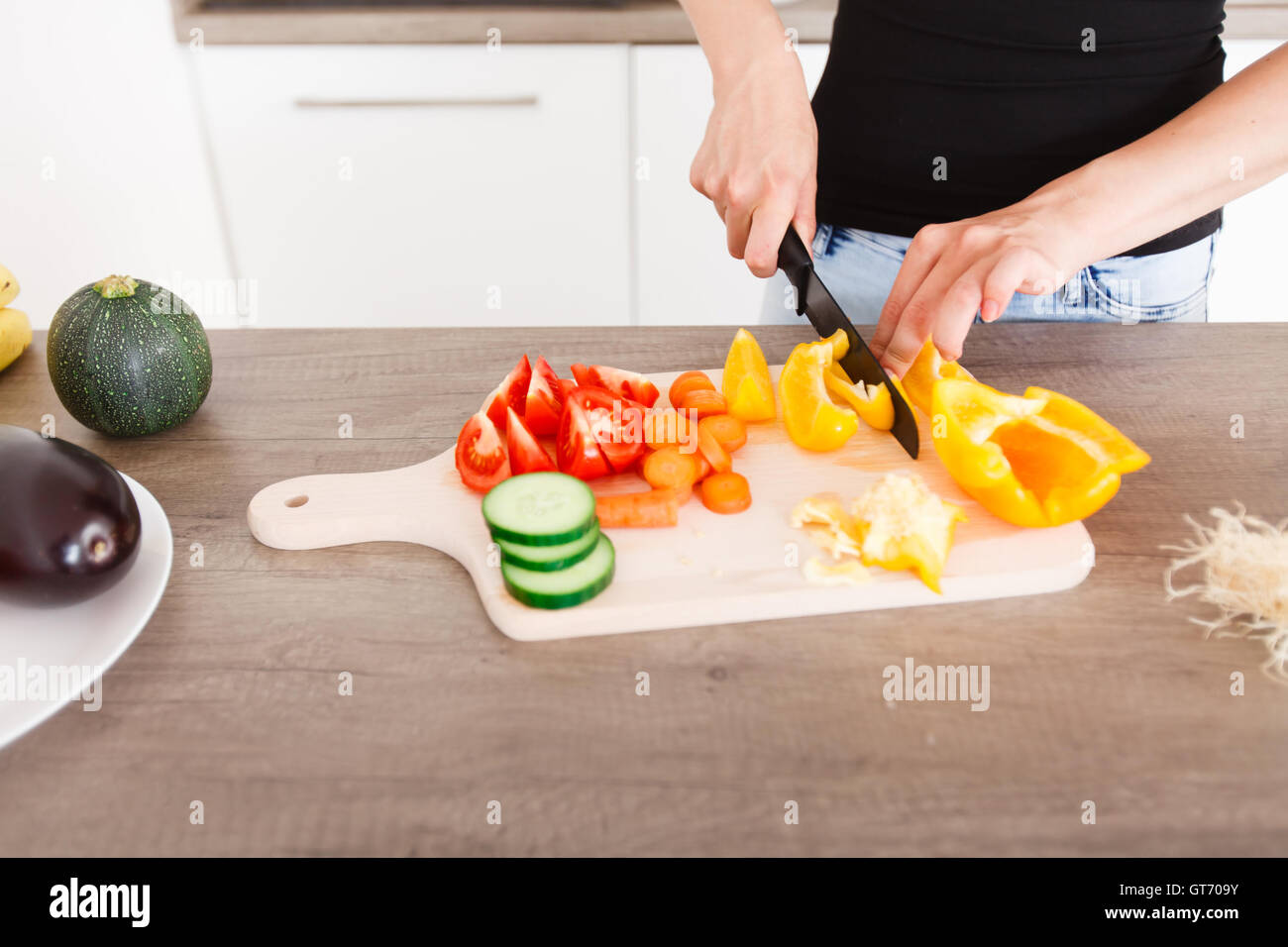 langhaarige junge Frau bereitet eine moderne und stilvolle Küche gesunde Gemüsesalat Stockfoto